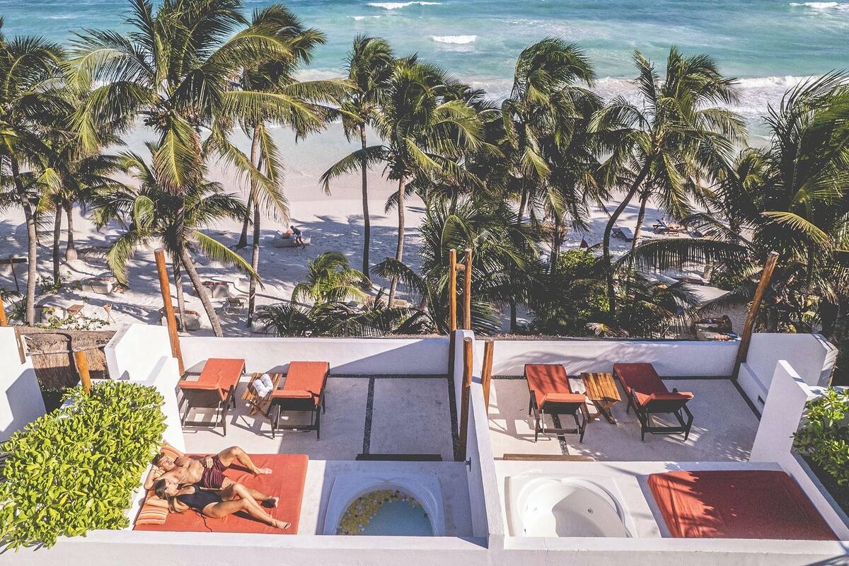 A rooftop terrace with lounge chairs, a small pool, and a view of the beach and ocean.