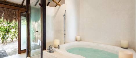 A modern bathroom with a freestanding bathtub, a glass shower enclosure, and two candles on the side.