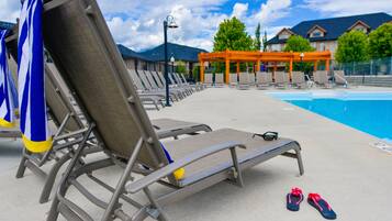 A poolside area with lounge chairs, a pool, and a covered seating area.