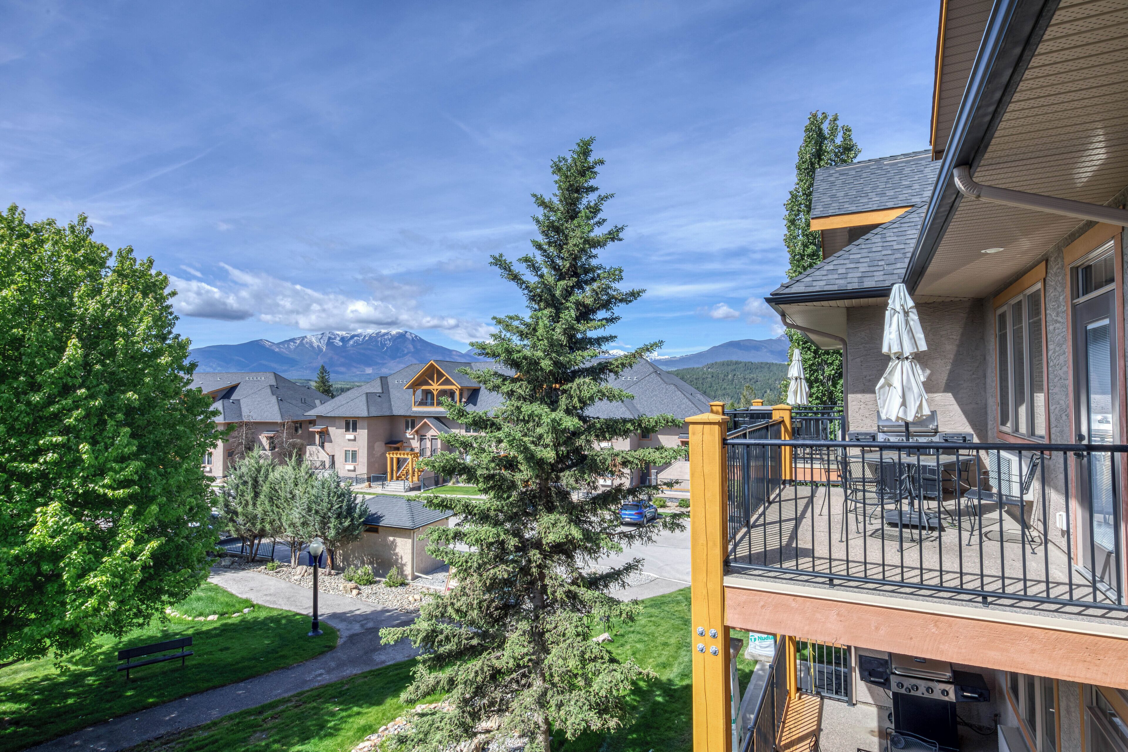 A residential area with a balcony, a grill, and a view of mountains.