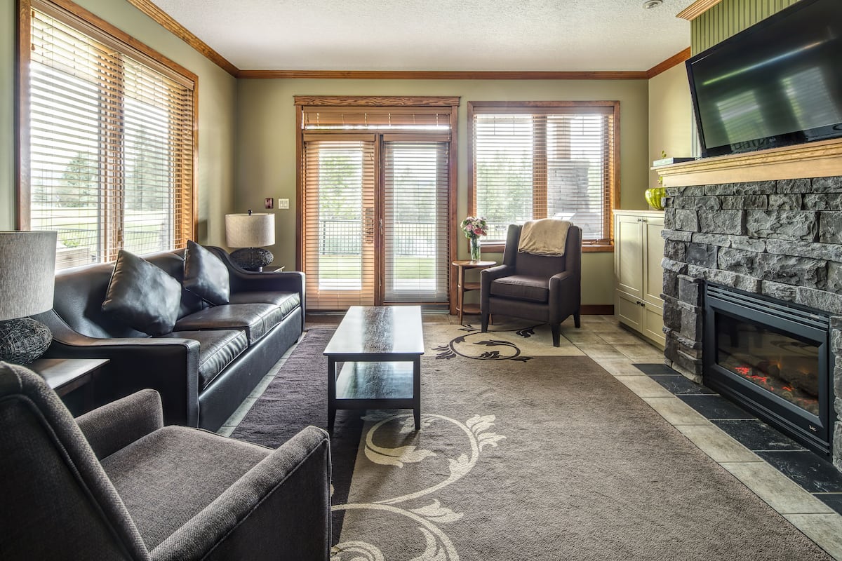 A living room with a fireplace, a sofa, a coffee table, and a TV.