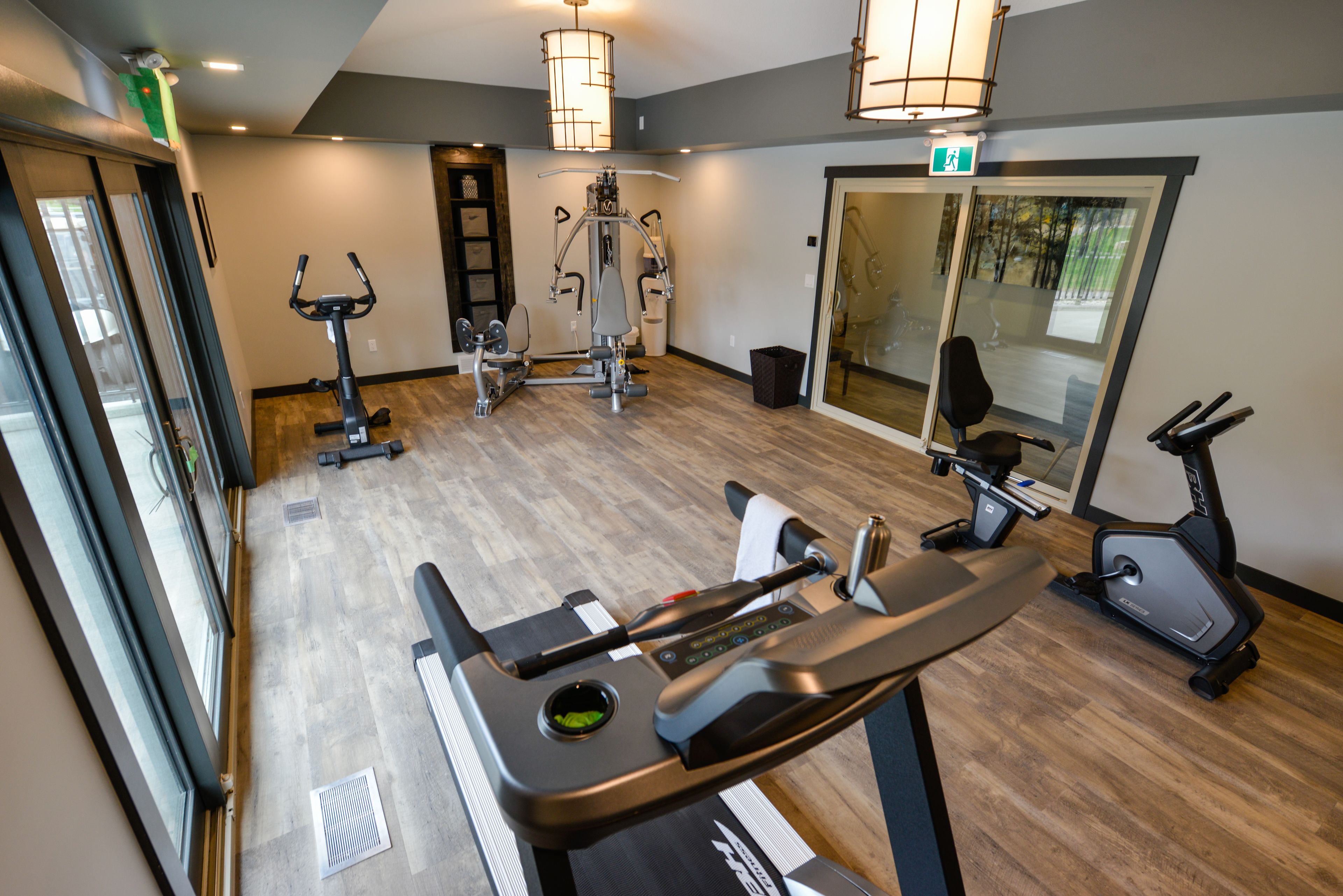 A gym with exercise equipment, a treadmill, and a mirrored wall.