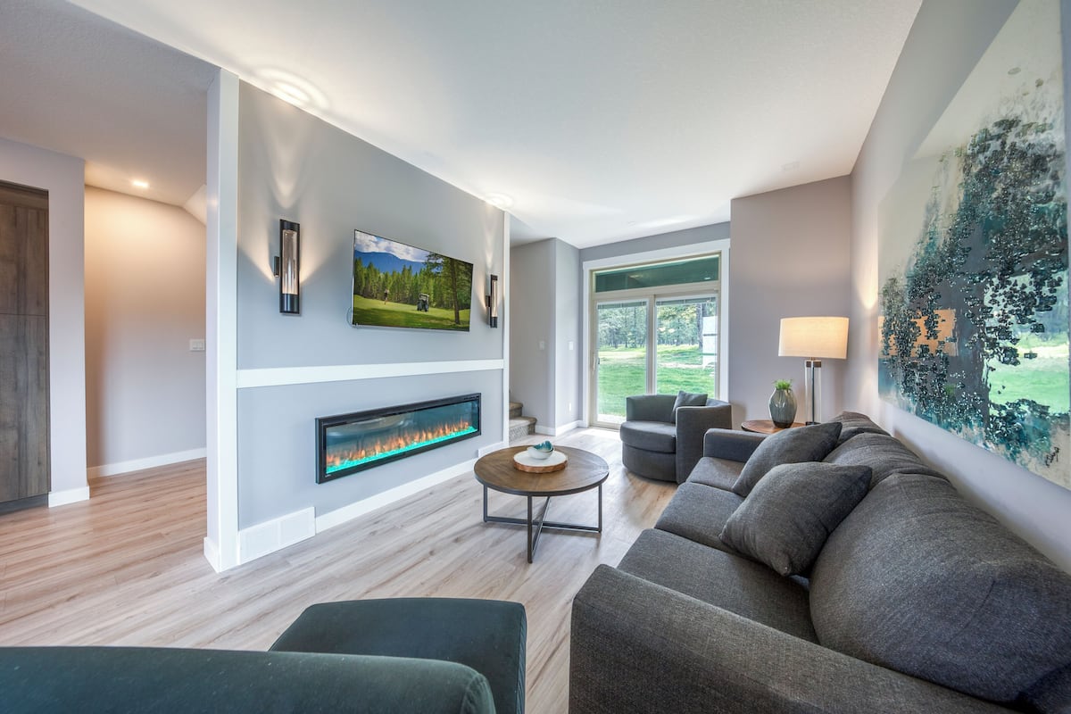 A modern living room with a fireplace, a large window, and a contemporary couch.