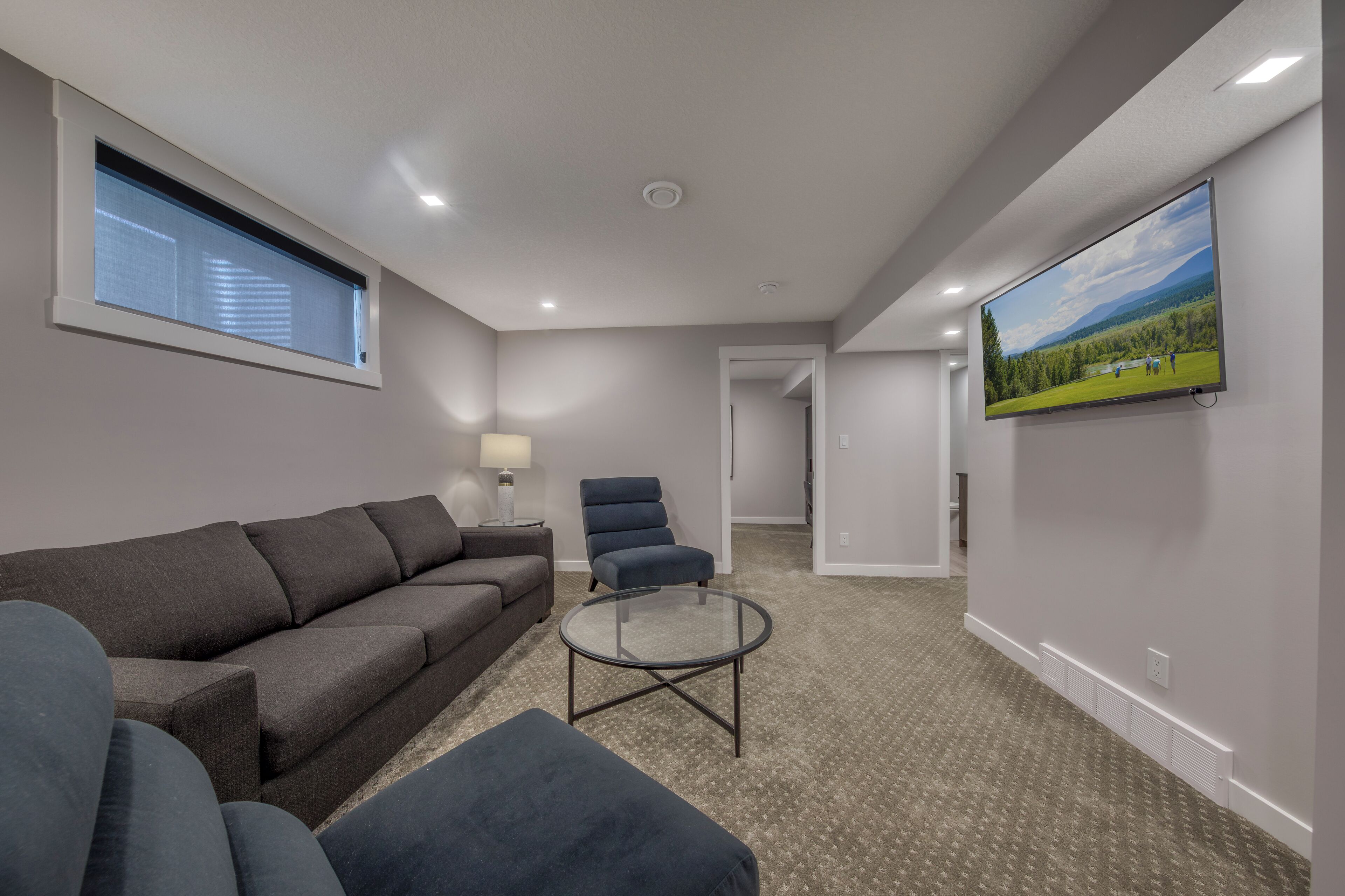 A modern living room with a sofa, armchair, and a glass coffee table.