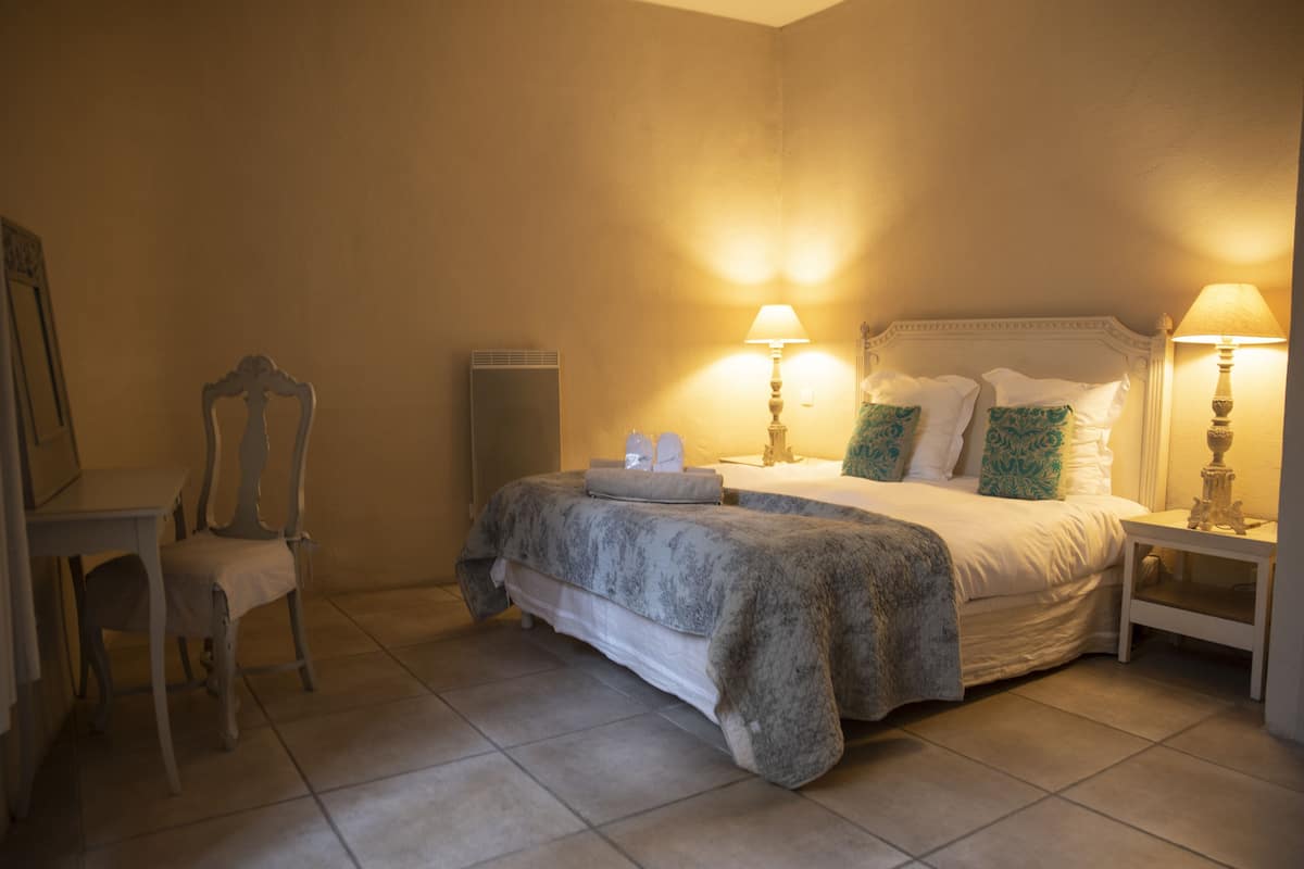 A bedroom with a bed, two bedside tables with lamps, a chair, and a dresser.