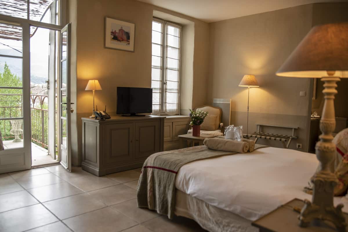 A bedroom with a bed, a television, a window, and a balcony.