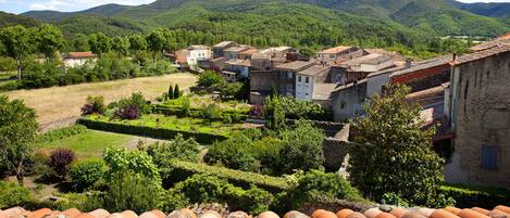 A village with traditional architecture, terraced gardens, and a mountainous backdrop.