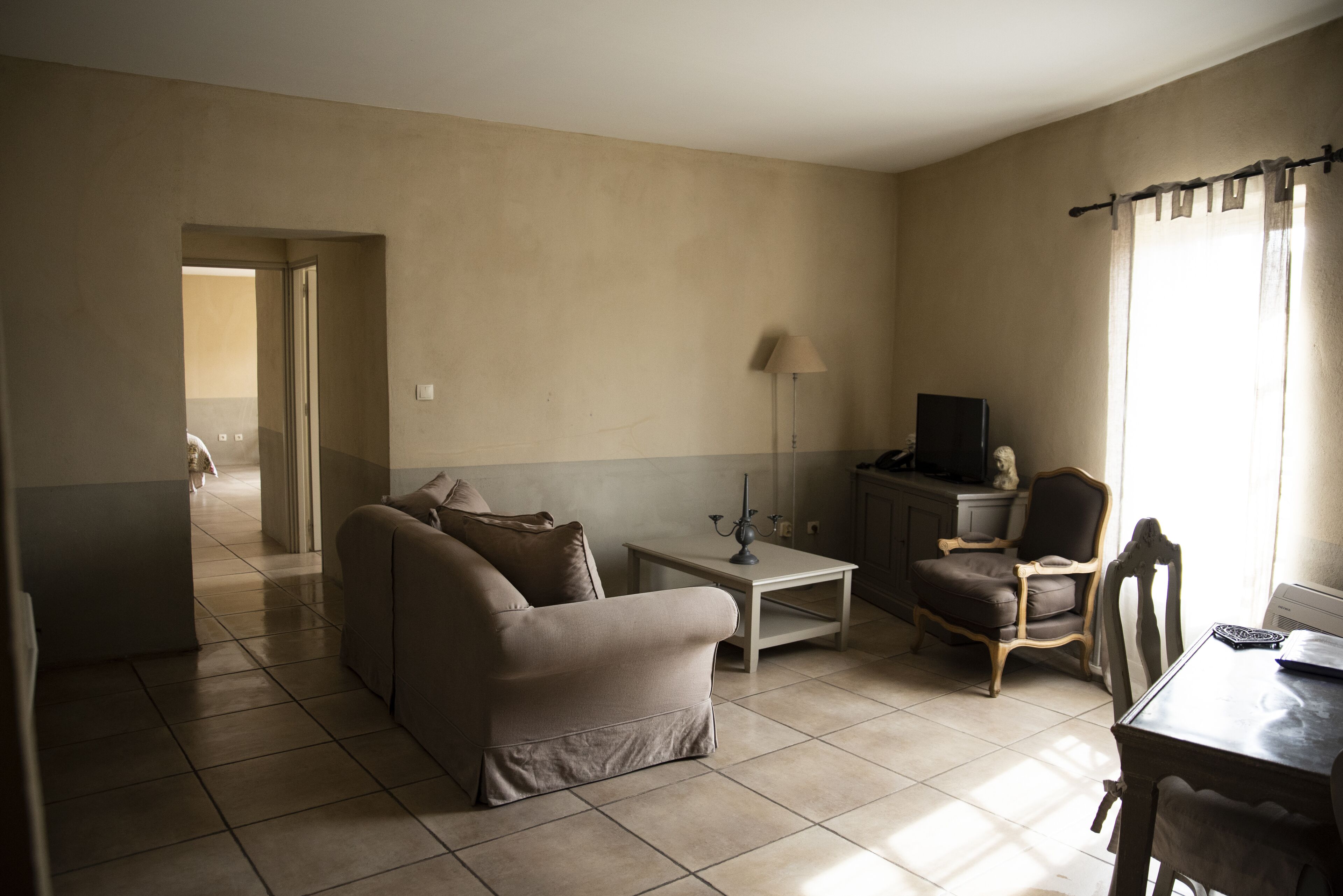 A living room with a sofa, a coffee table, a TV, and a dining table.