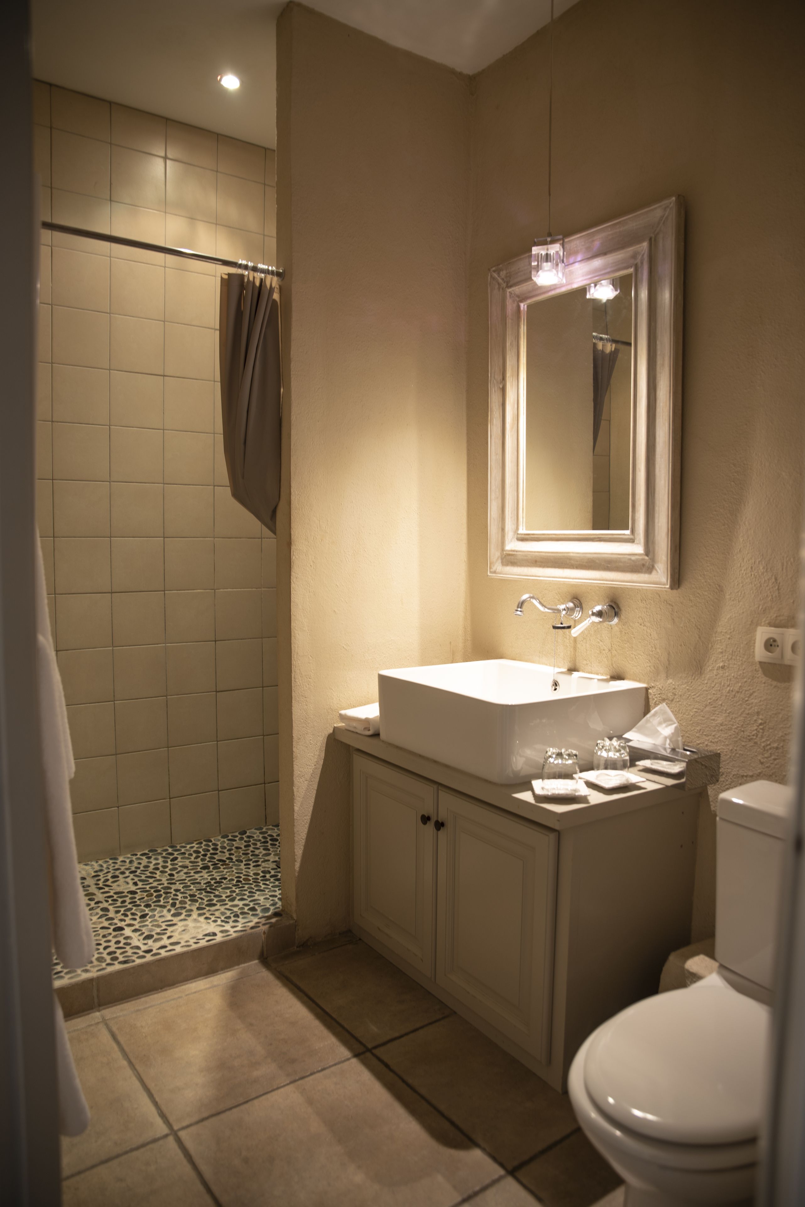 Une salle de bain équipée d’une douche, de toilettes, d’un lavabo et d’un miroir.