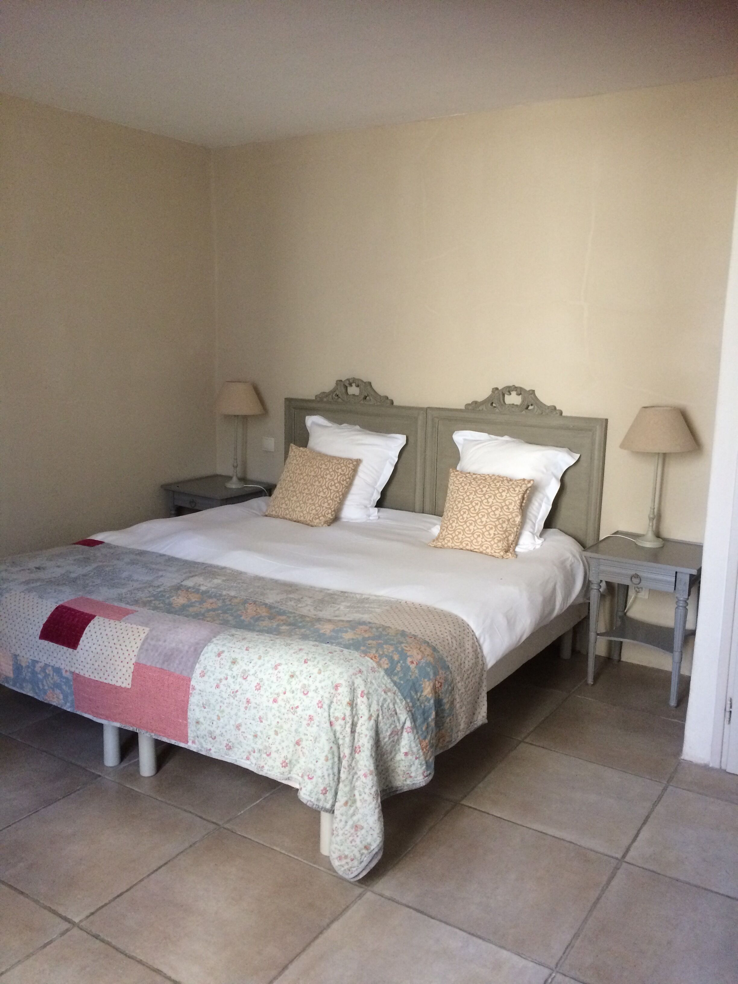 A neatly made bed with a floral bedspread and two decorative pillows, flanked by bedside tables with lamps.