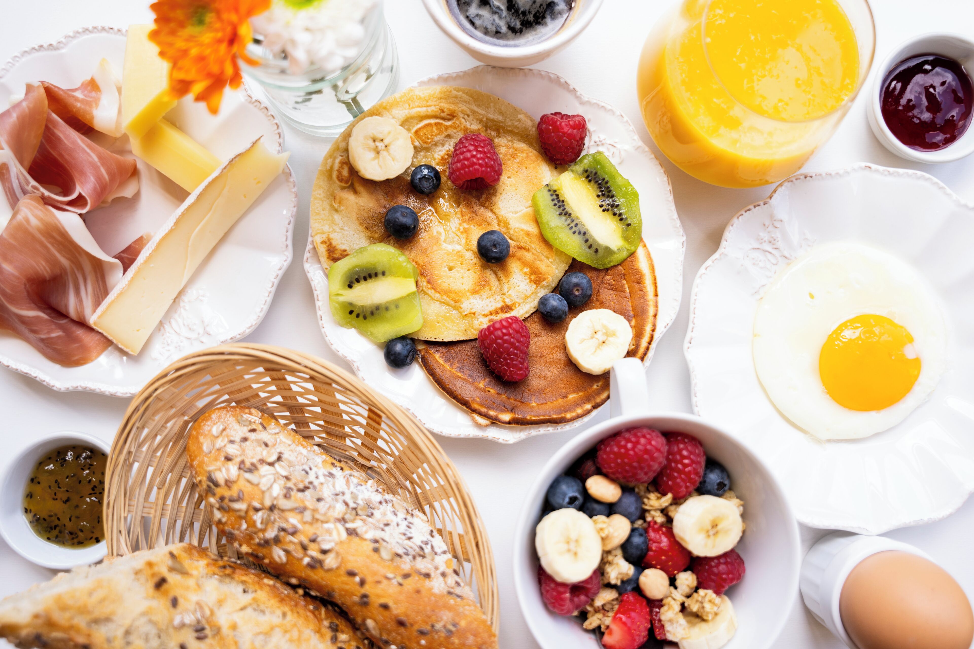 A breakfast spread with pancakes, fruits, eggs, and bread.