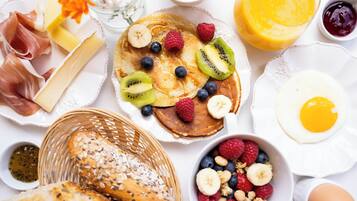 A breakfast spread with pancakes, fruits, eggs, and bread.