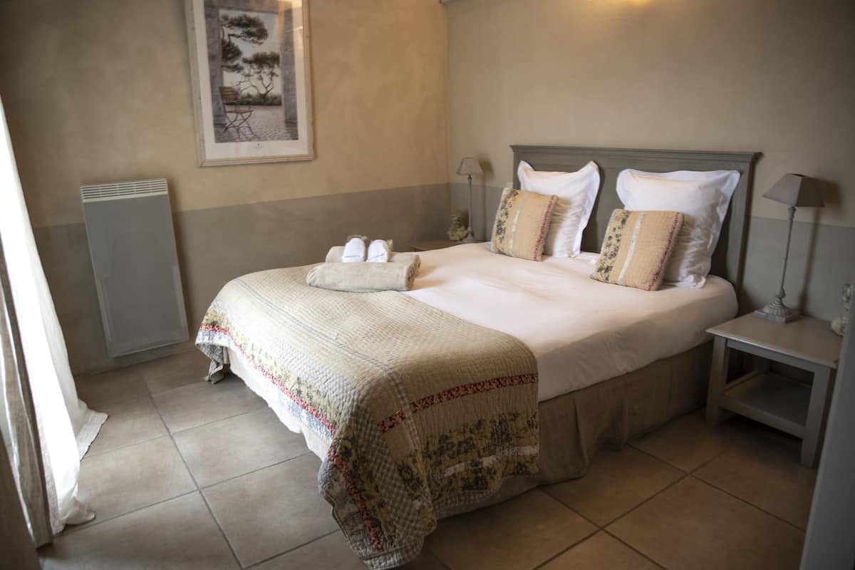 A neatly made bed with a quilt, pillows, and a bedside table with a lamp.
