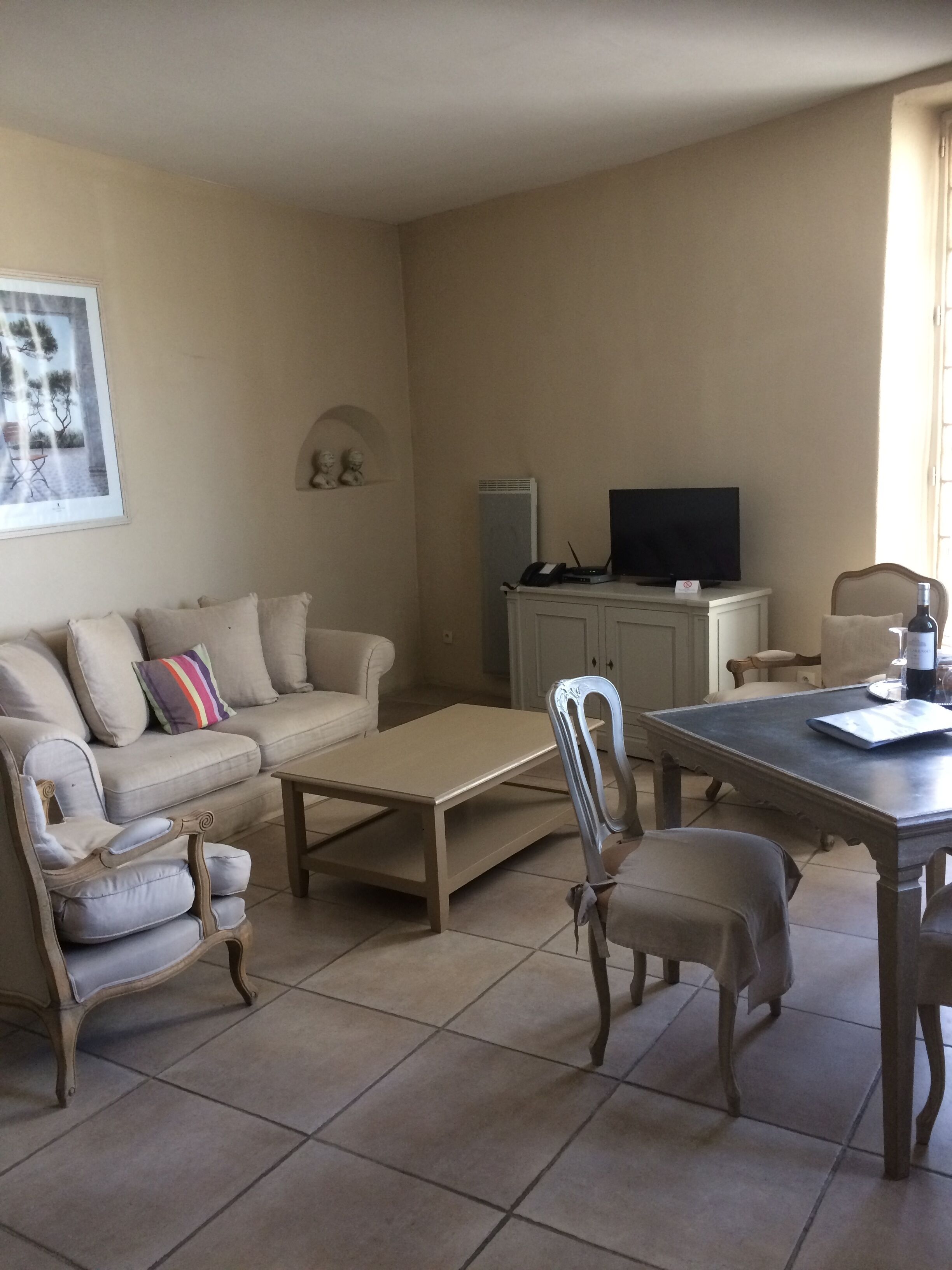 Una sala de estar con un sofá, dos sillones, una mesa de centro, una mesa de comedor con sillas, un televisor y un mueble.