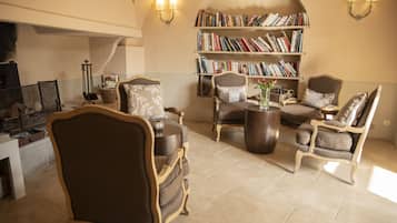 A cozy living room with a fireplace, comfortable seating, a bookshelf, and a coffee table.