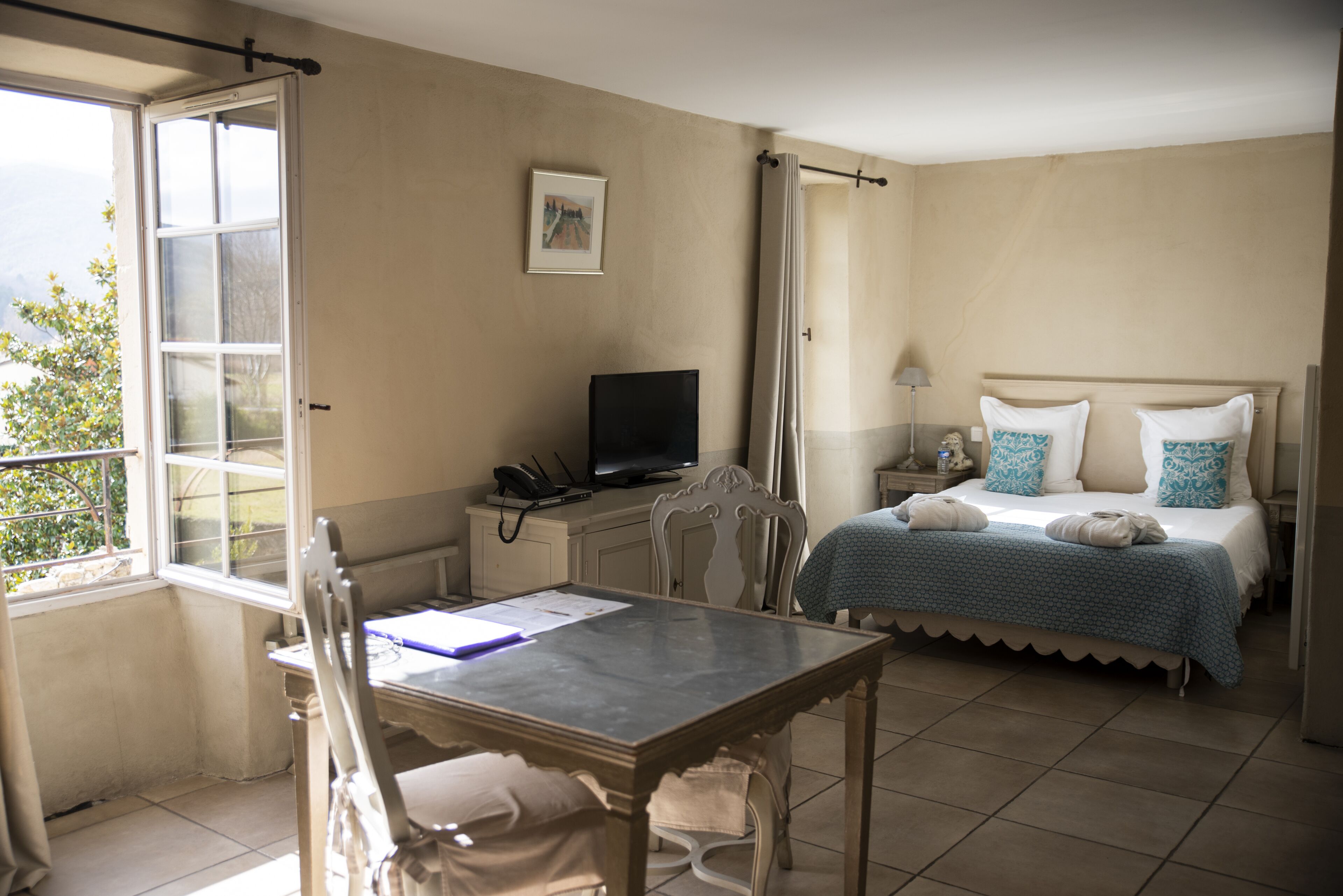 Camera d'albergo con un letto, una scrivania con un computer, una sedia e una finestra vista panoramica.