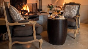 A cozy living room with a fireplace, two armchairs, a coffee table, and a wall-mounted light fixture. - Couvent d'Hérépian (Herepian)