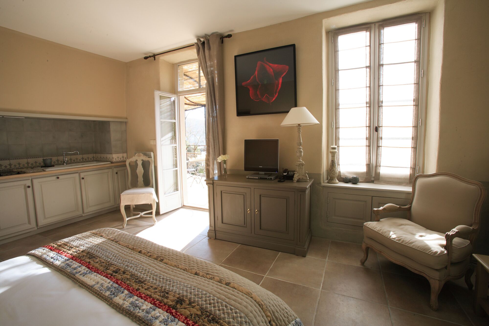A hotel room with a bed, a desk, a television, and a window with curtains.