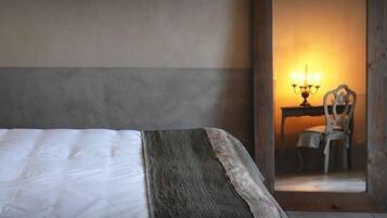 A hotel room with a bed, pillows, a lamp, a chair, and a table with a candelabra.