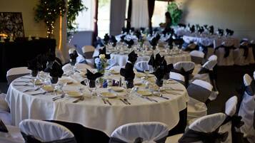 A banquet hall with round tables set for a formal event, featuring white tablecloths and black napkins.