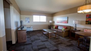A spacious living room with a sofa, coffee table, and a dining area with a table and chairs.