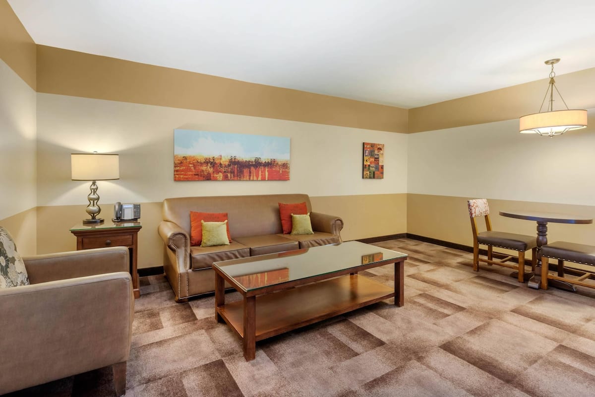 A living room with a sofa, armchair, coffee table, lamp, and artwork on the walls.