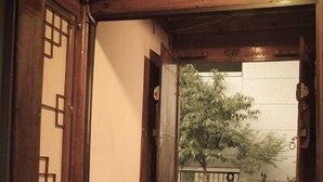 A traditional Japanese-style room with tatami flooring, a low wooden table, and a sliding door leading to a garden. - iCOS Guesthouse 1 for Female - Hostel (Seoul)