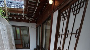 A narrow hallway with a wooden bench, tiled flooring, and a traditional Japanese-style door with a lattice design. - iCOS Guesthouse 1 for Female - Hostel (Seoul)
