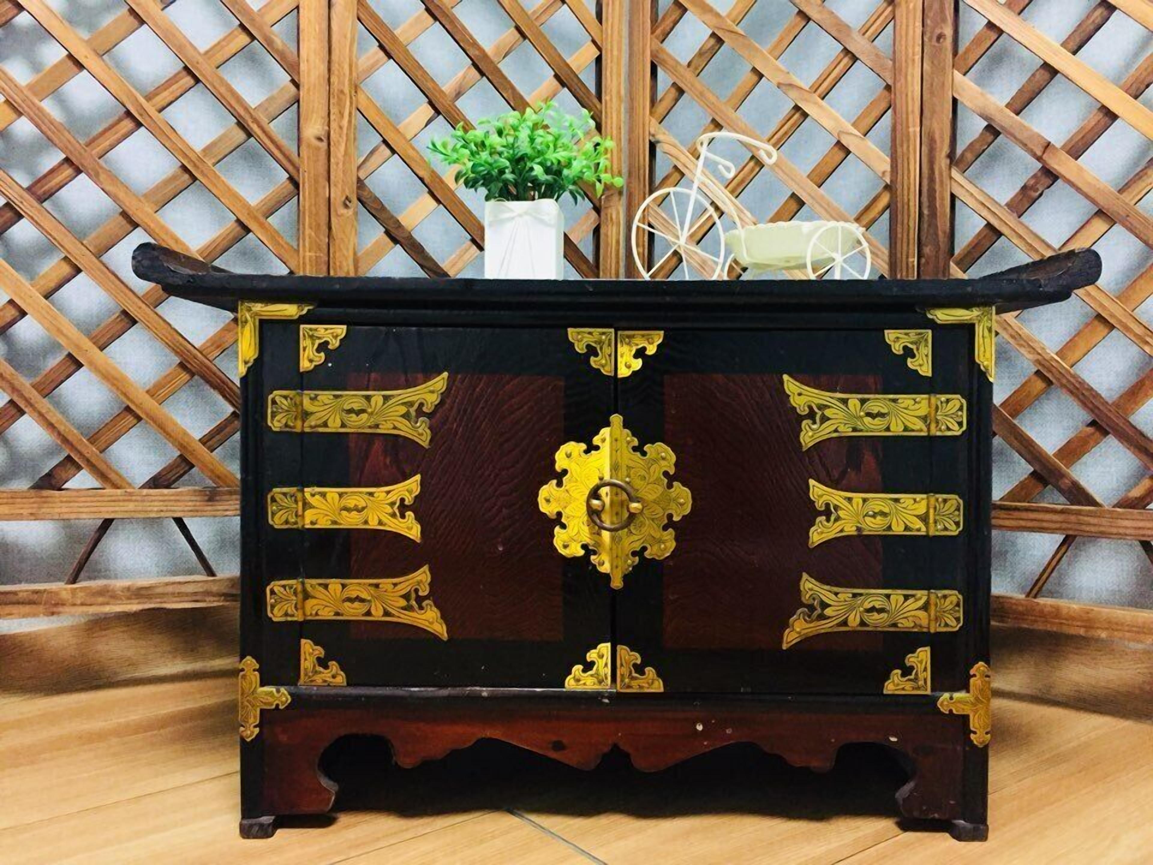 Un aparador de madera con detalles ornamentales dorados sobre un fondo de celosía.