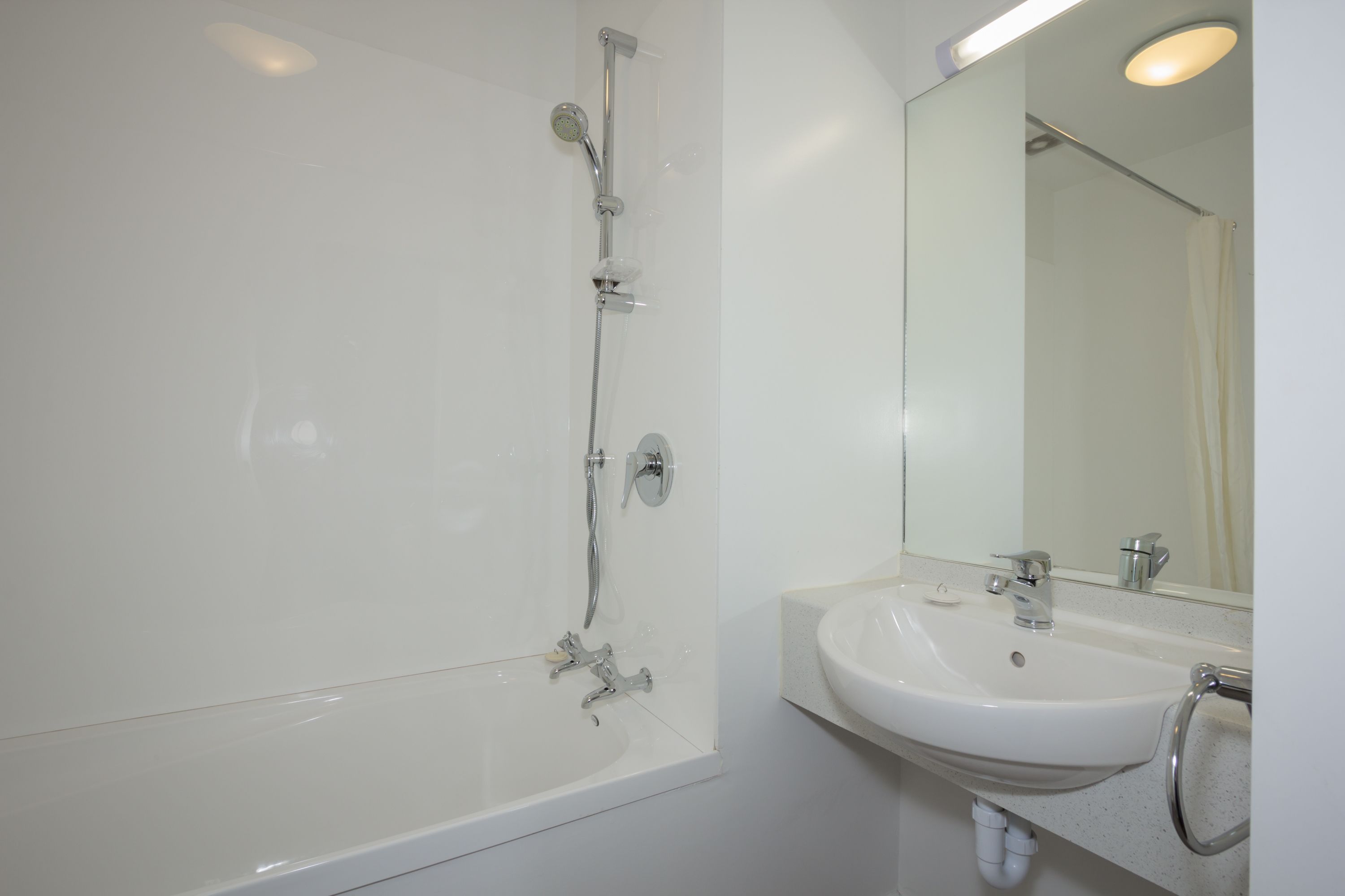 A bathroom with a bathtub, a sink, and a mirror.