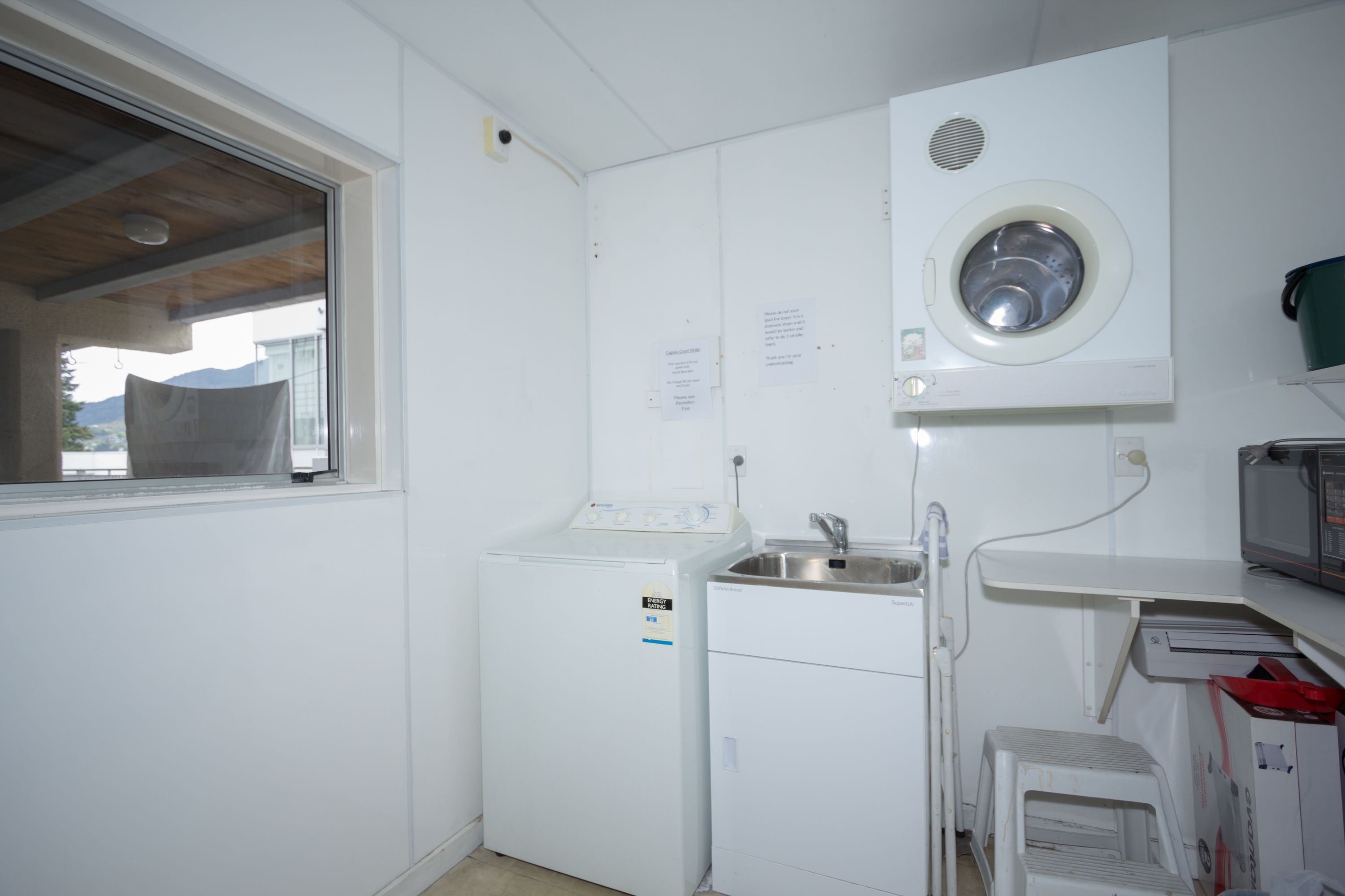 A compact laundry room with a washing machine, a dryer, a sink, and a microwave.