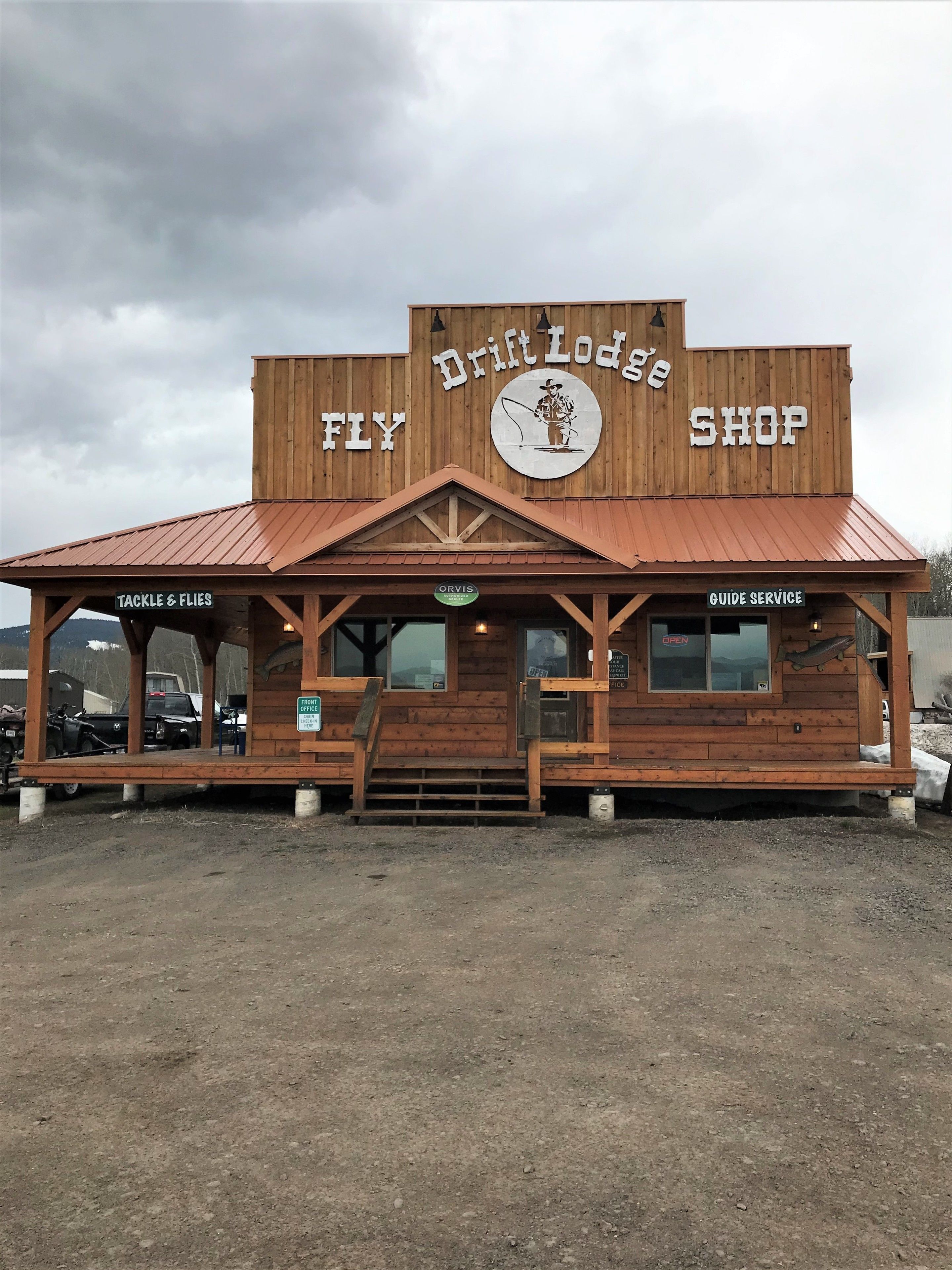 A rustic wooden building with a sign reading "Drift Lodge Fly Shop."