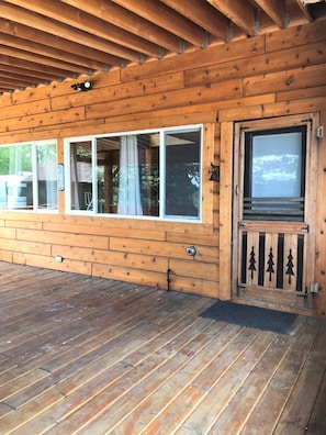 A wooden cabin with a covered porch, large windows, and a door with a decorative gate. - Drift Lodge & Fly Shop (Island Park)
