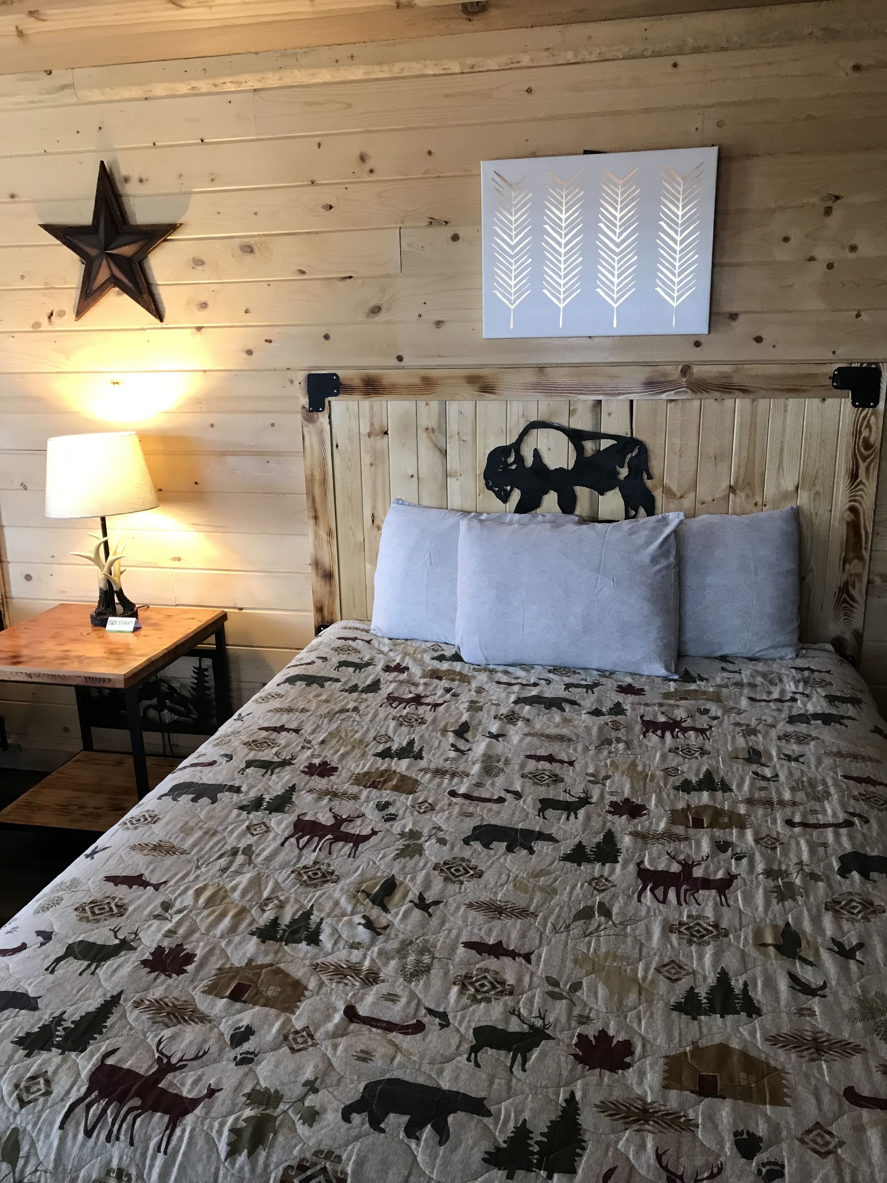 A bed with a quilted blanket featuring animal and nature patterns, a wooden headboard, and a star decoration on the wall.