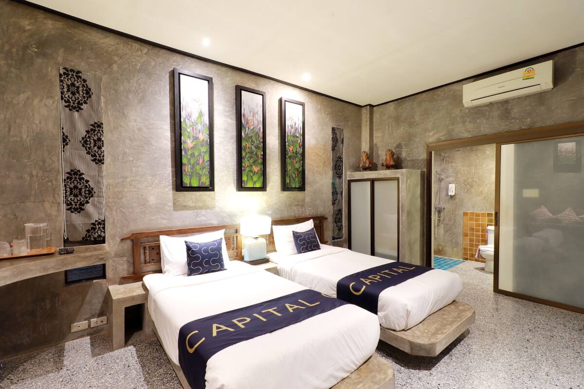 A hotel room with two beds, a vanity with a mirror, and artwork on the walls.