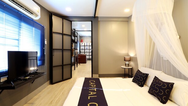 A hotel room with a bed, a TV, and a desk. - Capital O 464 At Nata Chiangmai Chic Jungle (Mae Rim)