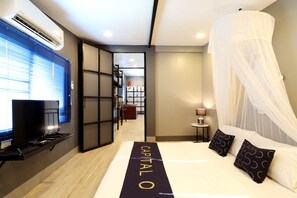 A hotel room with a bed, a TV, and a desk. - Capital O 464 At Nata Chiangmai Chic Jungle (Mae Rim)