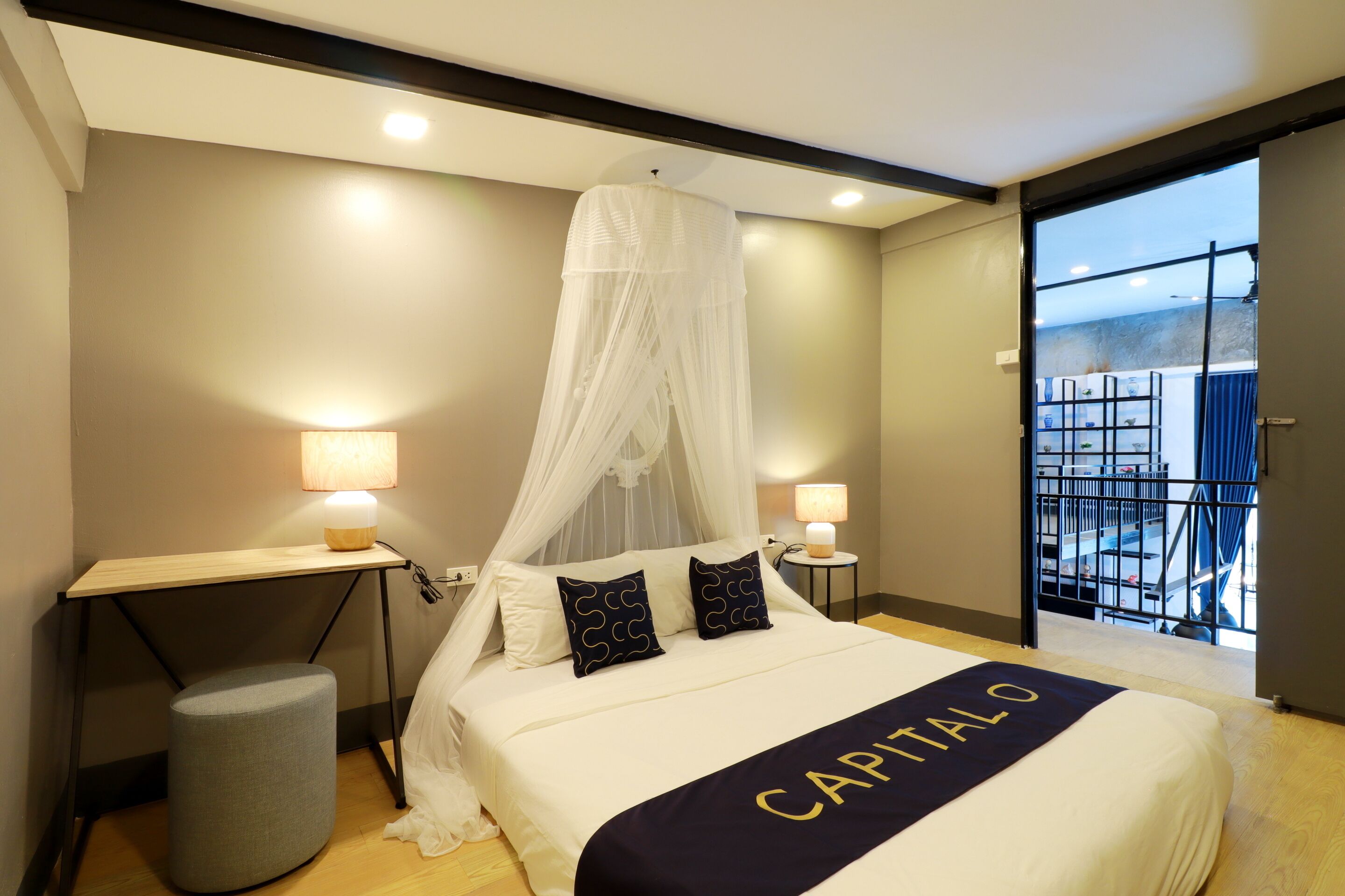 A hotel room with a bed, two bedside tables, a chair, a window with a view, and a balcony.