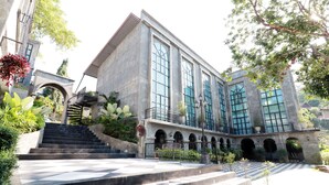 A building with a modern architectural style, featuring large windows and a central staircase leading to an upper level. - Capital O 464 At Nata Chiangmai Chic Jungle (Mae Rim)
