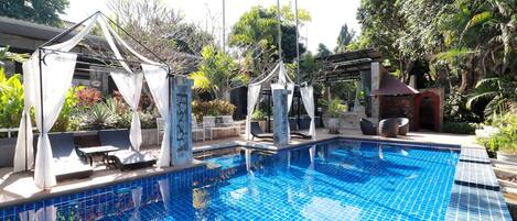 Een buitenzwembad, ligstoelen bij het zwembad