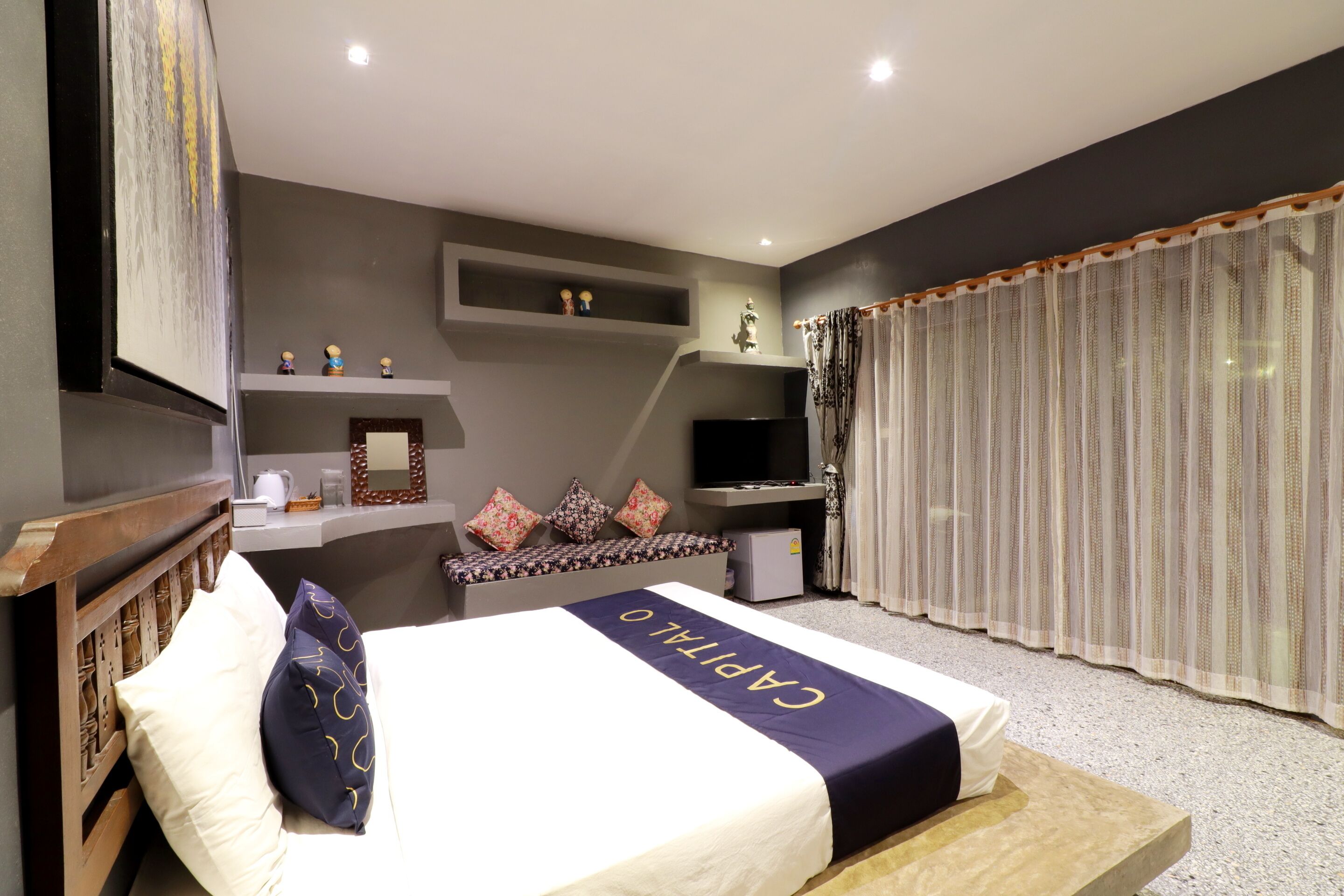A hotel room with a bed, a television, a small desk, and a window with curtains.
