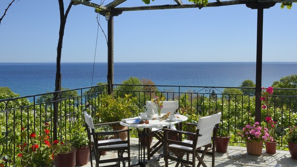 Une terrasse avec une table dressée pour deux personnes, donnant sur la mer.