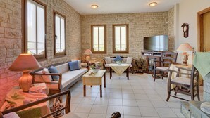 Un salon spacieux avec un mur en pierre, de grandes fenêtres, un canapé, une table basse et un téléviseur.