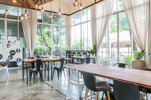 A spacious cafe with large windows, wooden tables, and black and white chairs.