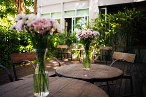 A round wooden table with two clear glass vases containing flowers, surrounded by wooden chairs.