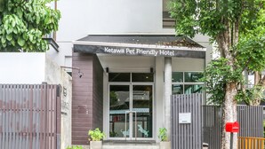 La entrada al Hotel Kotawa que acepta mascotas, con una fachada moderna, una puerta de cristal y un pequeño escalón que conduce a la entrada.