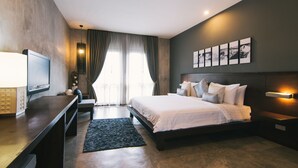 Habitación de hotel moderna con una cama grande, televisor de pantalla plana, escritorio y un ventanal con cortinas.