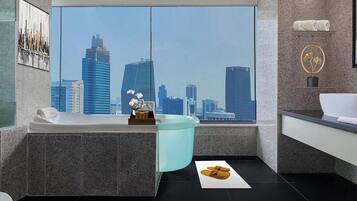 A modern bathroom with a large window, a bathtub, a sink, and a mirror.