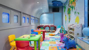 Una sala de juegos infantil con muebles coloridos, un espacio para jugar y juguetes educativos.