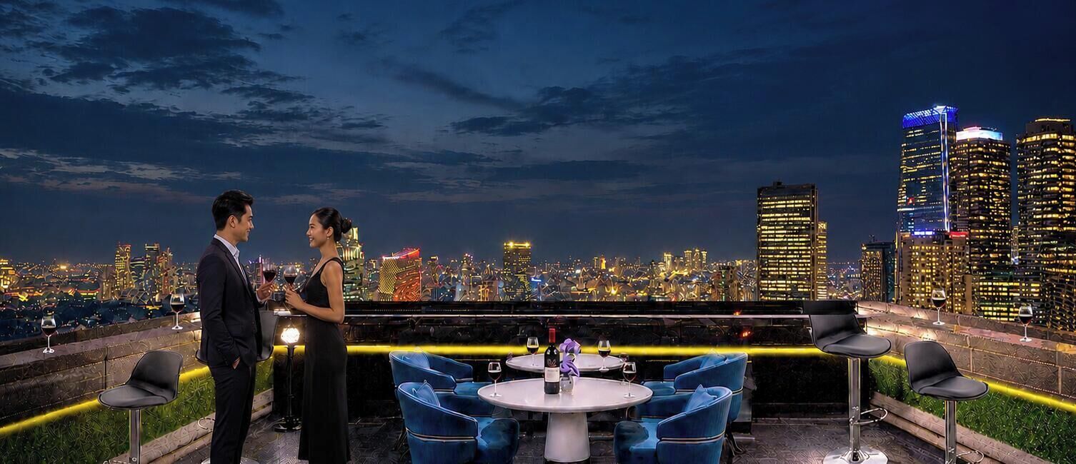 Una pareja en un bar en la azotea con vistas al horizonte urbano, mesas con sillas y botellas de vino.